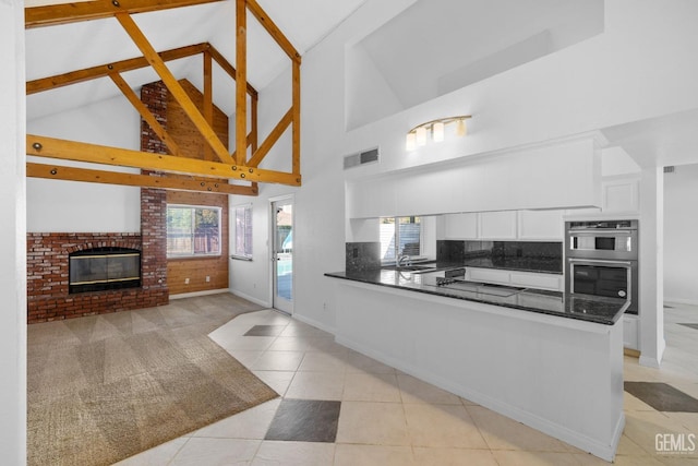 kitchen featuring visible vents, a sink, dark countertops, white cabinetry, and double oven