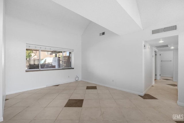 tiled spare room with baseboards, visible vents, and high vaulted ceiling