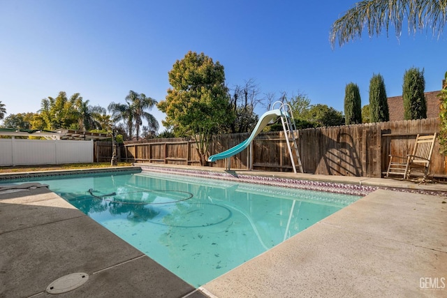 view of swimming pool with a patio, a fenced in pool, a fenced backyard, and a water slide