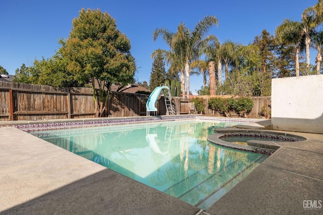 view of pool with a fenced in pool, an in ground hot tub, a water slide, and a fenced backyard