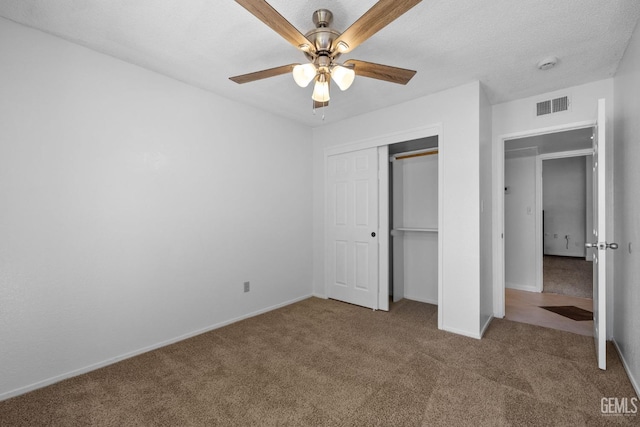 unfurnished bedroom featuring baseboards, visible vents, a closet, a textured ceiling, and carpet flooring