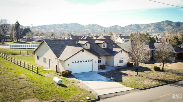 view of front of home with stucco siding, a mountain view, fence, a garage, and driveway