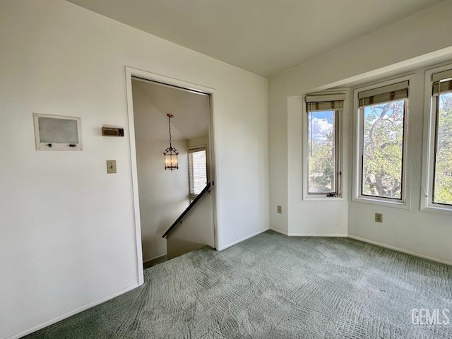 spare room featuring light carpet and an inviting chandelier