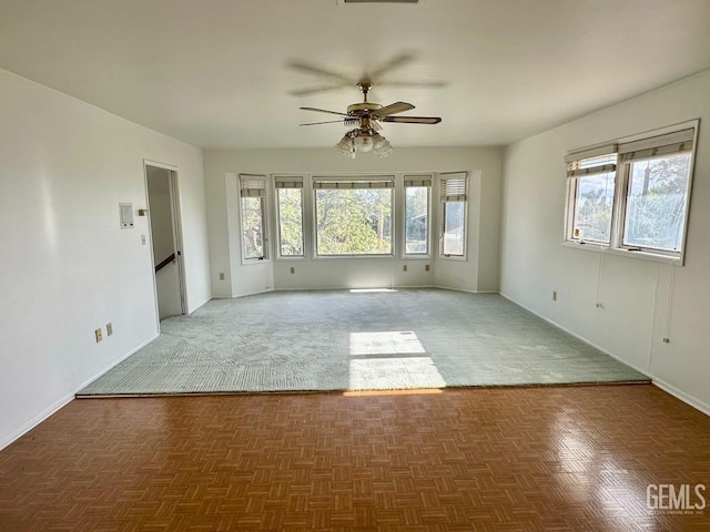 unfurnished room with ceiling fan and dark parquet flooring