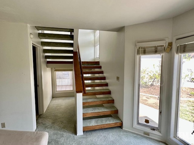 staircase featuring beamed ceiling, carpet floors, and a wealth of natural light