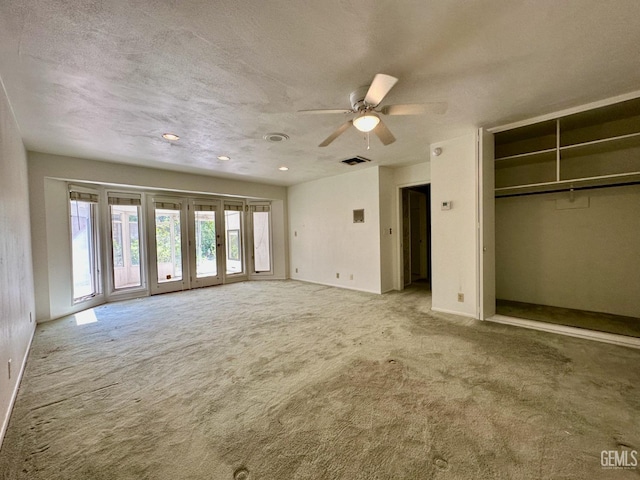 unfurnished bedroom featuring light carpet, a textured ceiling, a closet, and ceiling fan