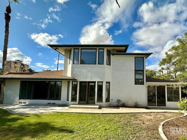 back of house with a lawn and a patio