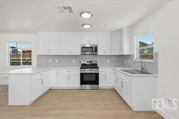 664 Fresno Ave, Shafter, CA 93263 - kitchen featuring stainless steel appliances, a peninsula, light countertops, tasteful backsplash, and white cabinets