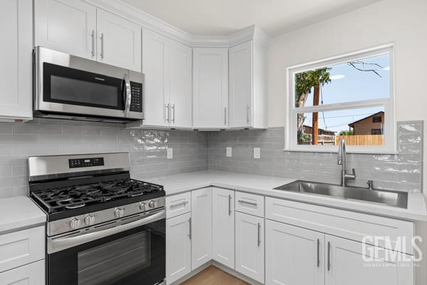 664 Fresno Ave, Shafter, CA 93263 - kitchen with stainless steel appliances, light countertops, white cabinetry, and tasteful backsplash