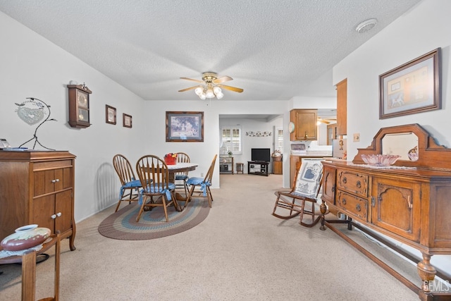 dining area with light carpet, a textured ceiling, and ceiling fan