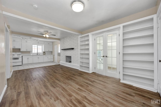 2805 Charleston Dr, Bakersfield, CA 93308 - unfurnished living room featuring beamed ceiling, a ceiling fan, wood finished floors, a brick fireplace, and french doors