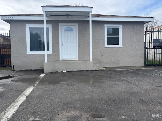 entrance to property with a gate, stucco siding, and fence