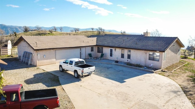 view of front facade featuring a mountain view, stucco siding, a chimney, and a tile roof