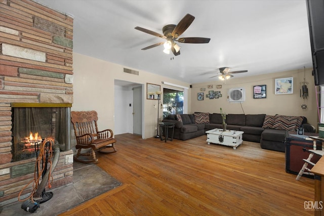 living room with a stone fireplace, ceiling fan, and hardwood / wood-style flooring