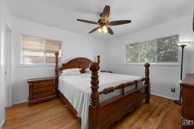 bedroom featuring hardwood / wood-style flooring, ceiling fan, and multiple windows