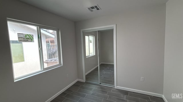 unfurnished bedroom with a closet, baseboards, multiple windows, and visible vents