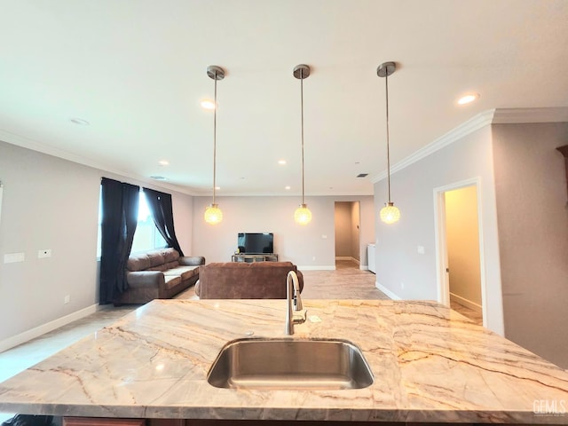 kitchen with an island with sink, light stone countertops, sink, and ornamental molding