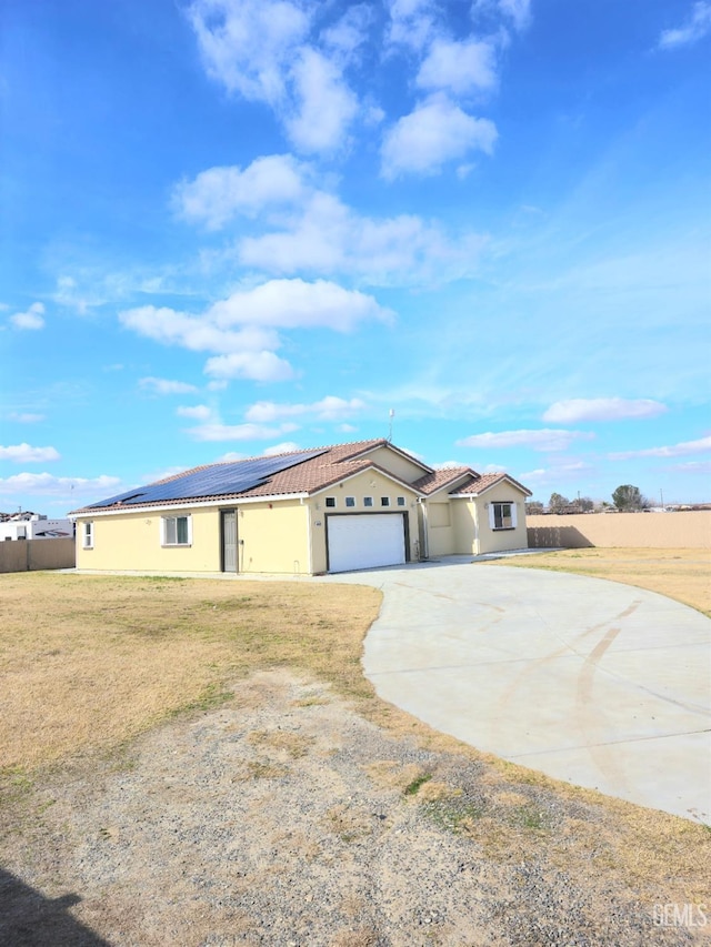 ranch-style house featuring a garage, a front yard, and solar panels