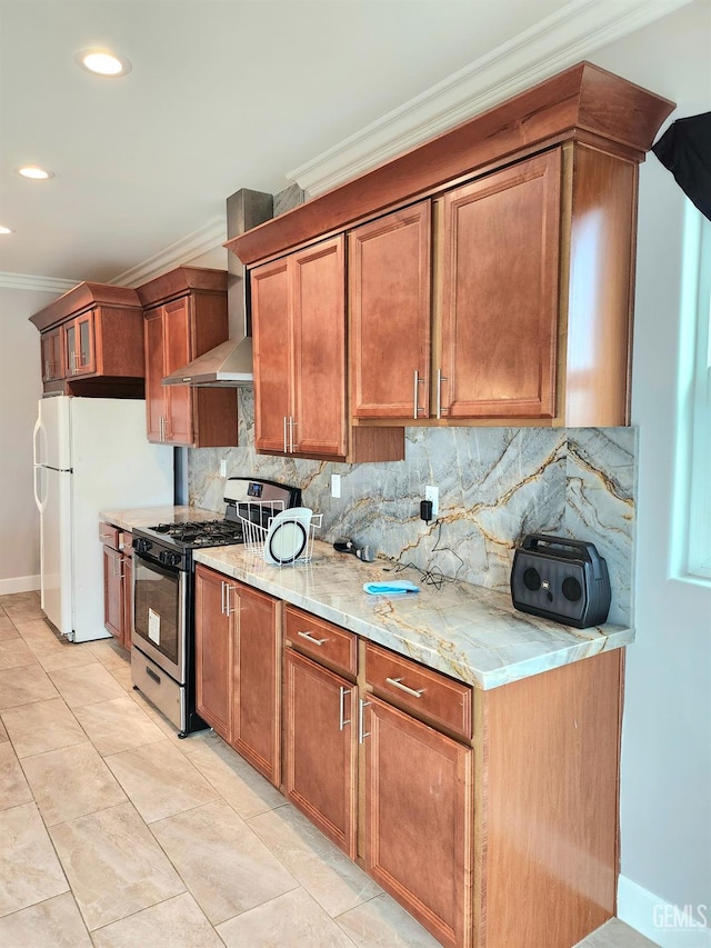 kitchen with gas range, crown molding, light stone counters, backsplash, and wall chimney range hood