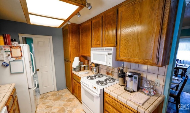 kitchen featuring tasteful backsplash, white appliances, and tile countertops