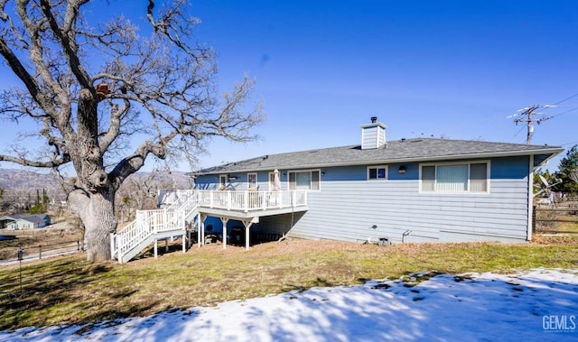 rear view of house featuring a wooden deck and a lawn