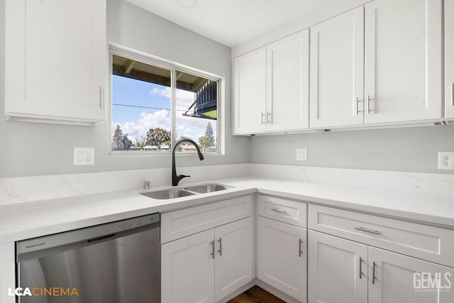 kitchen featuring stainless steel dishwasher, white cabinets, light stone countertops, and a sink