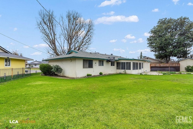 back of house featuring a yard, fence, a sunroom, and stucco siding