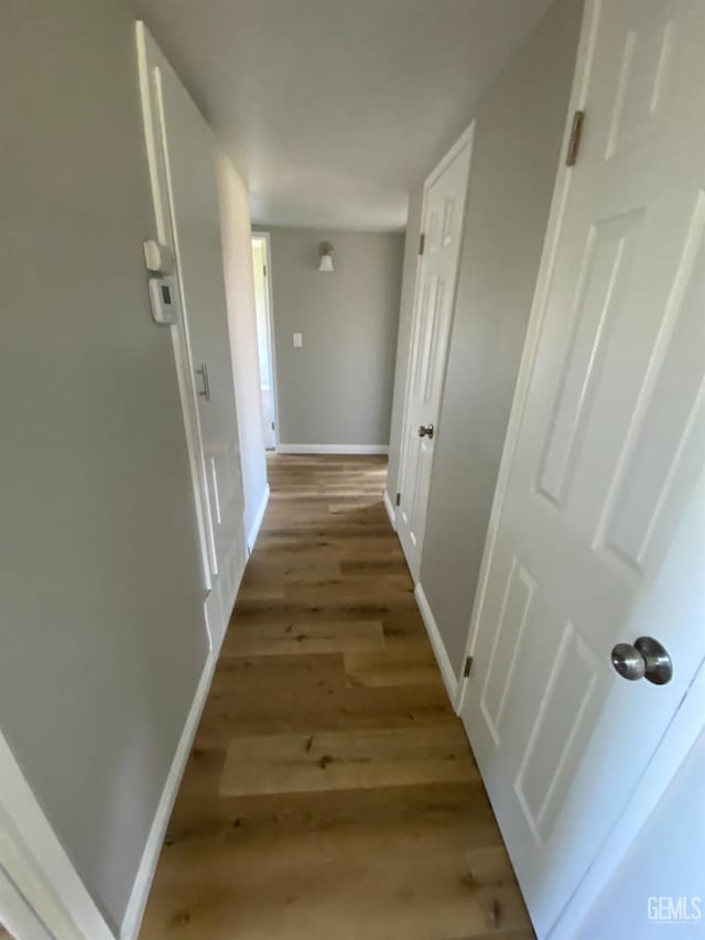 hallway featuring wood finished floors and baseboards