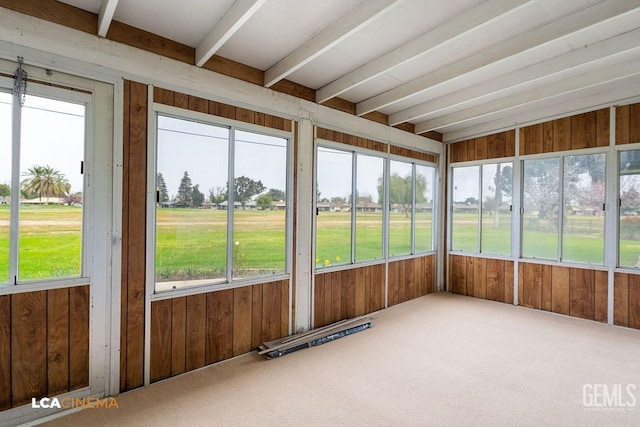 unfurnished sunroom featuring beamed ceiling and plenty of natural light