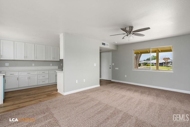 unfurnished living room with visible vents, carpet floors, baseboards, and ceiling fan