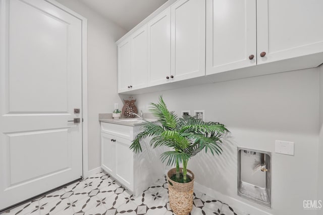 laundry area with light floors, hookup for a washing machine, cabinet space, a sink, and baseboards