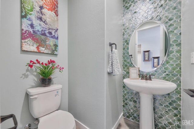 half bath featuring baseboards, a sink, and toilet