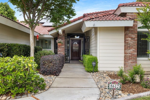 doorway to property featuring a tiled roof and roof mounted solar panels
