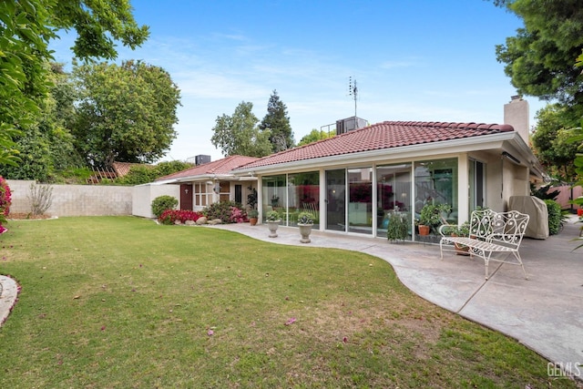 back of property featuring fence, a chimney, a patio area, a lawn, and a tile roof