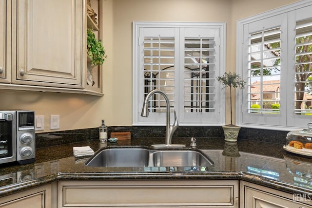 kitchen featuring a sink and dark stone countertops