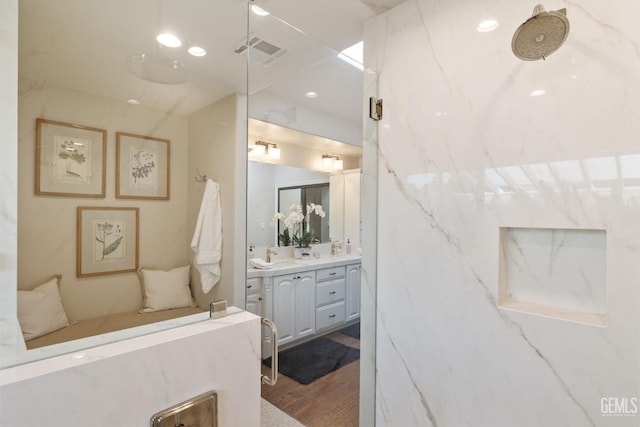 bathroom featuring visible vents, a marble finish shower, wood finished floors, and vanity