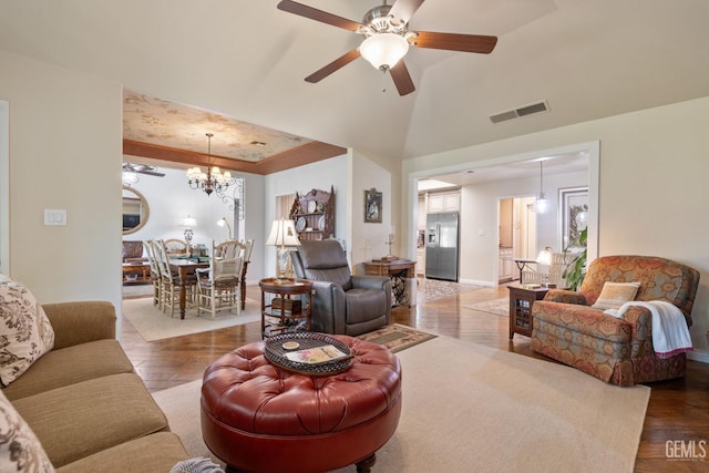 living area with ceiling fan with notable chandelier, wood finished floors, and visible vents