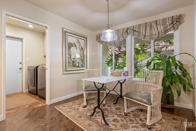 dining space featuring washing machine and clothes dryer, baseboards, and wood finished floors
