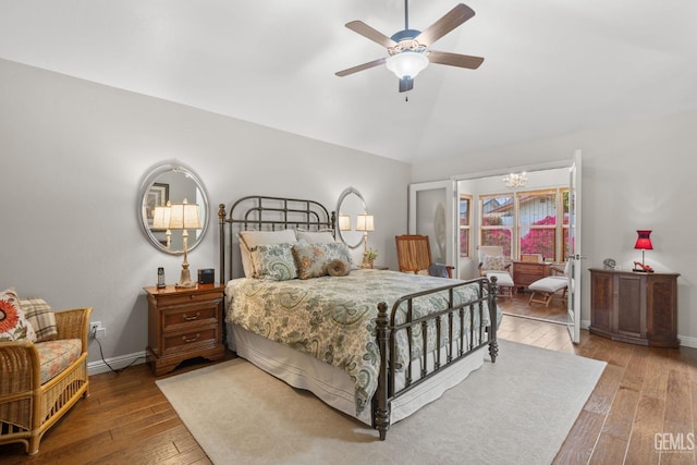 bedroom featuring baseboards, wood-type flooring, ceiling fan with notable chandelier, and lofted ceiling