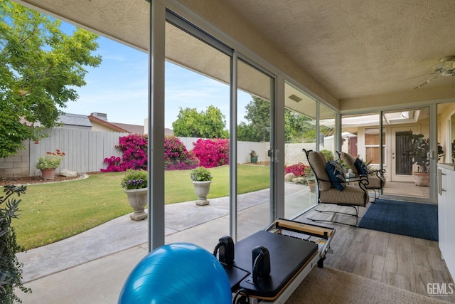interior space featuring a ceiling fan, a textured ceiling, wood finished floors, and a wealth of natural light