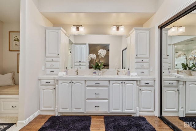 full bathroom with double vanity, a sink, and wood finished floors