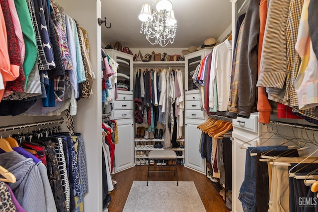 spacious closet featuring an inviting chandelier and dark wood-style floors
