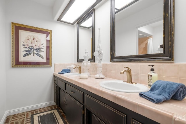 full bath with a sink, baseboards, brick floor, and double vanity