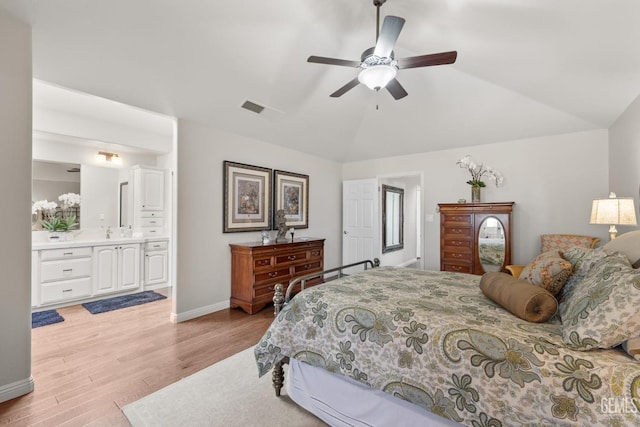 bedroom featuring visible vents, lofted ceiling, baseboards, a sink, and light wood finished floors