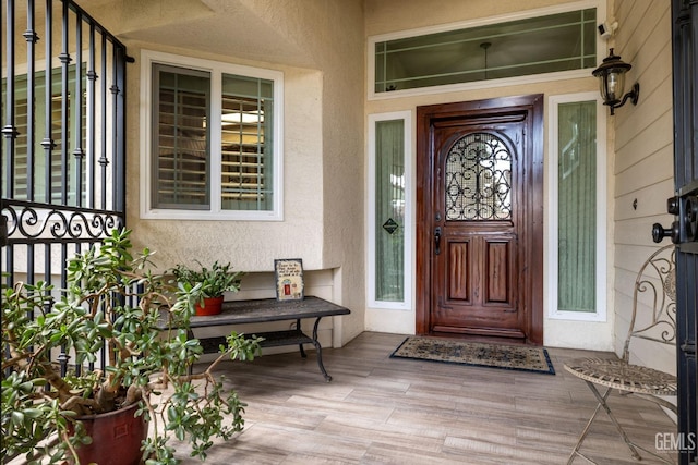 view of exterior entry with covered porch and stucco siding