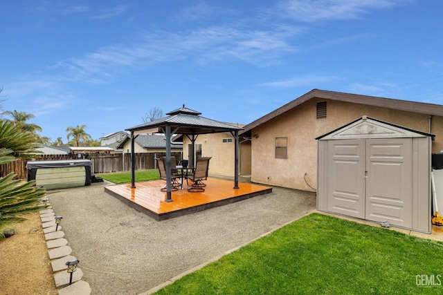 exterior space featuring an outbuilding, a hot tub, a gazebo, a storage shed, and fence