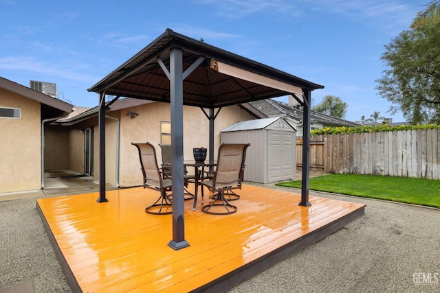 wooden deck featuring a storage shed, central AC unit, an outbuilding, fence, and outdoor dining area