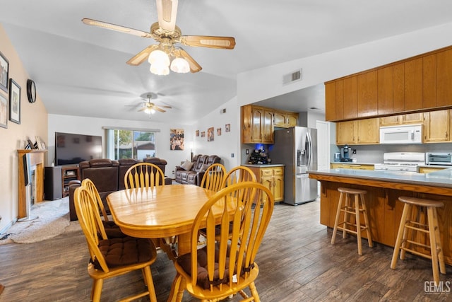 dining space featuring a toaster, visible vents, ceiling fan, dark wood-type flooring, and vaulted ceiling