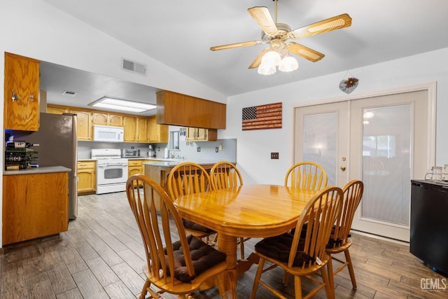 dining area featuring french doors, lofted ceiling, visible vents, a ceiling fan, and wood finished floors