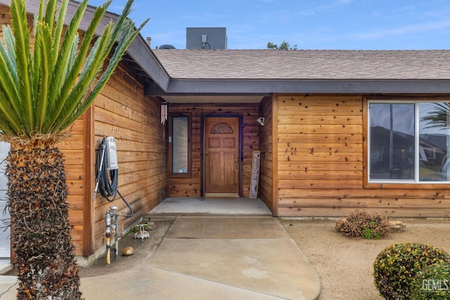 doorway to property with a shingled roof